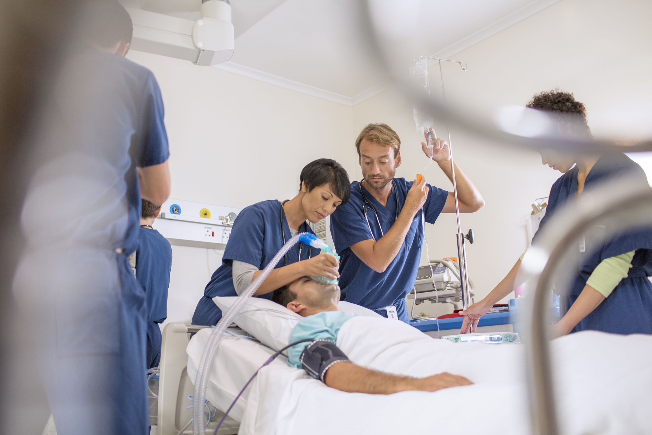 Doctor holding oxygen mask over patient, male doctor adjusting IV drip